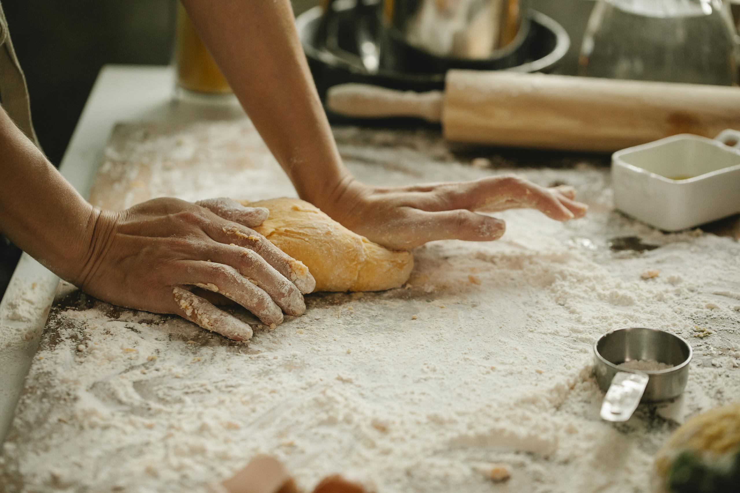 A person kneads fresh dough in a kitchen, showcasing the baking process.